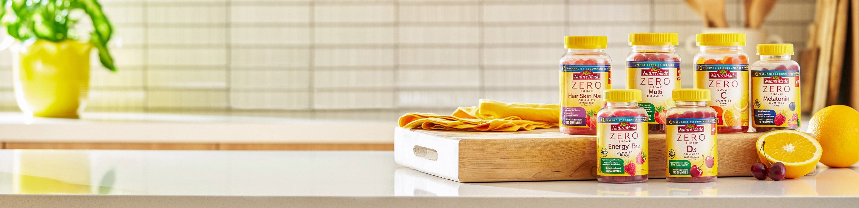 Nature Made Zero Sugar gummies displayed on kitchen counter with oranges and cherries.