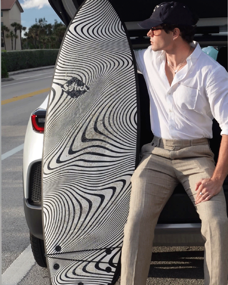 Taylor Reed poses with surfboard in Billy Reid.