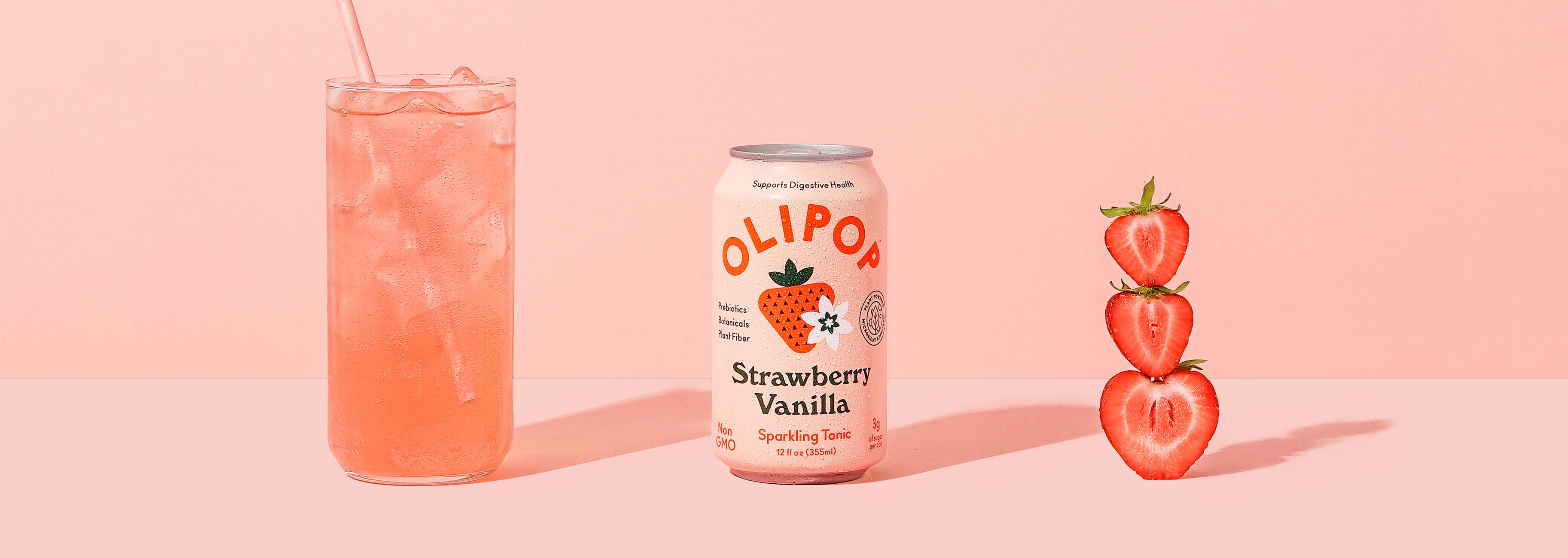 A photo of a glass of strawberry Vanilla on ice, a can of Strawberry Vanilla and slices of strawberries.