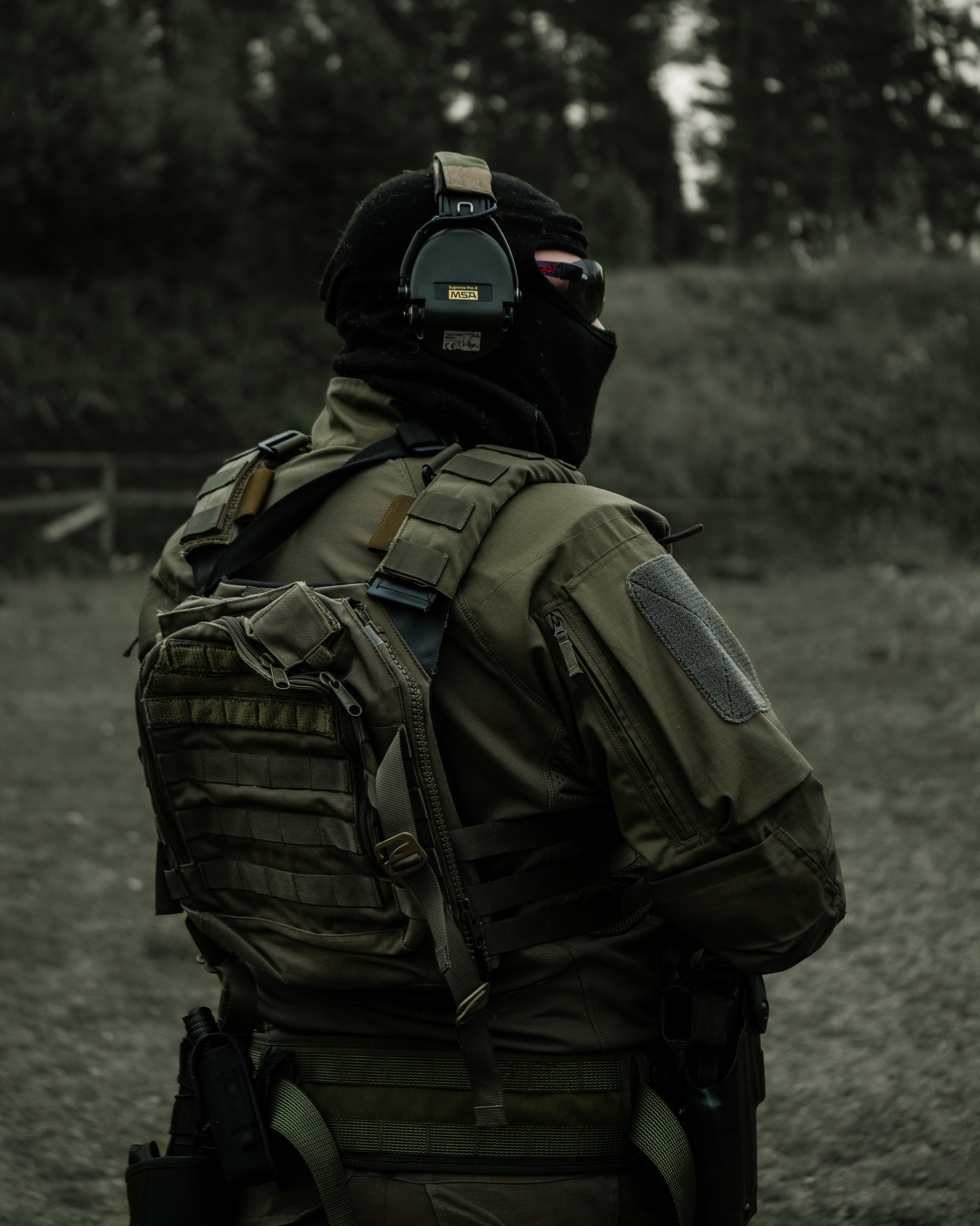 Man with a balaclava, sunglasses, headphones, earpro uf pro combat shirt, uf pro tactical pants, gunbelt and a plate carrier standing on shooting range. Finnish reservist