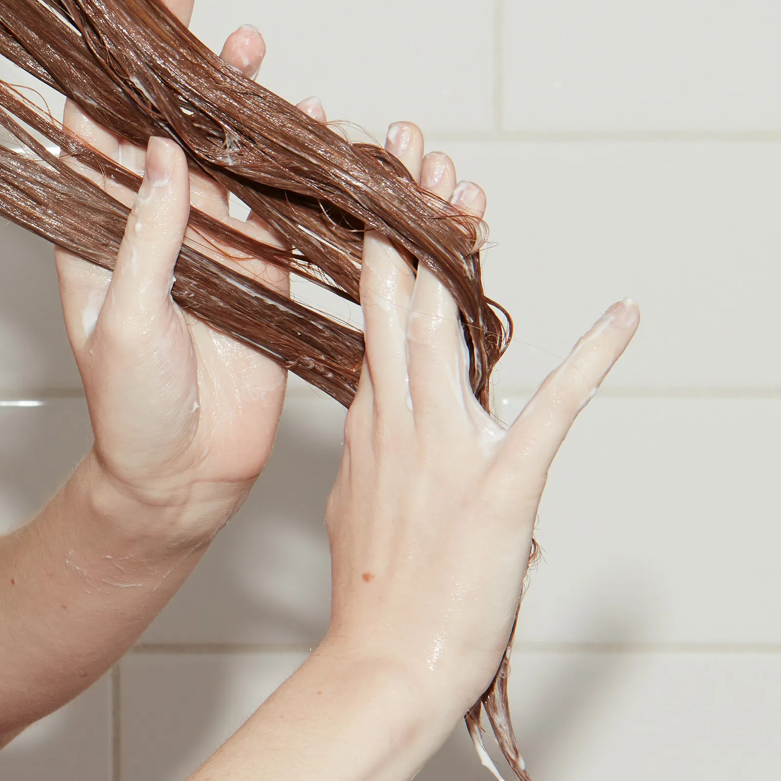 Closeup of fingers raking conditioner through wet hair