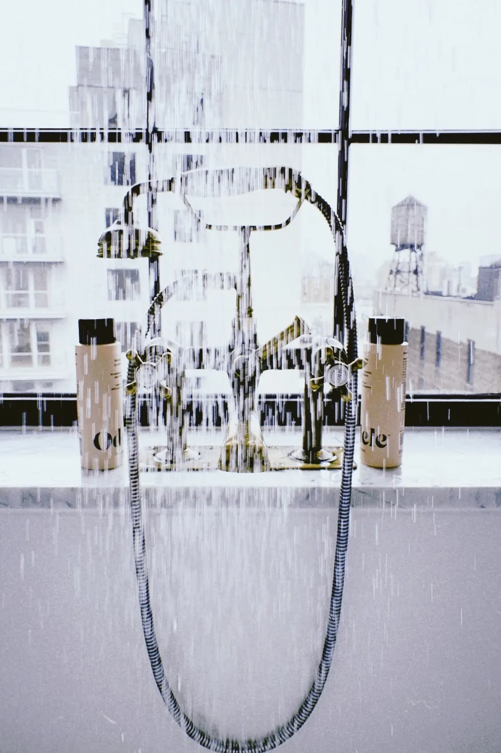 Odele Volumizing Shampoo and Conditioner on a shower ledge in front of a large window