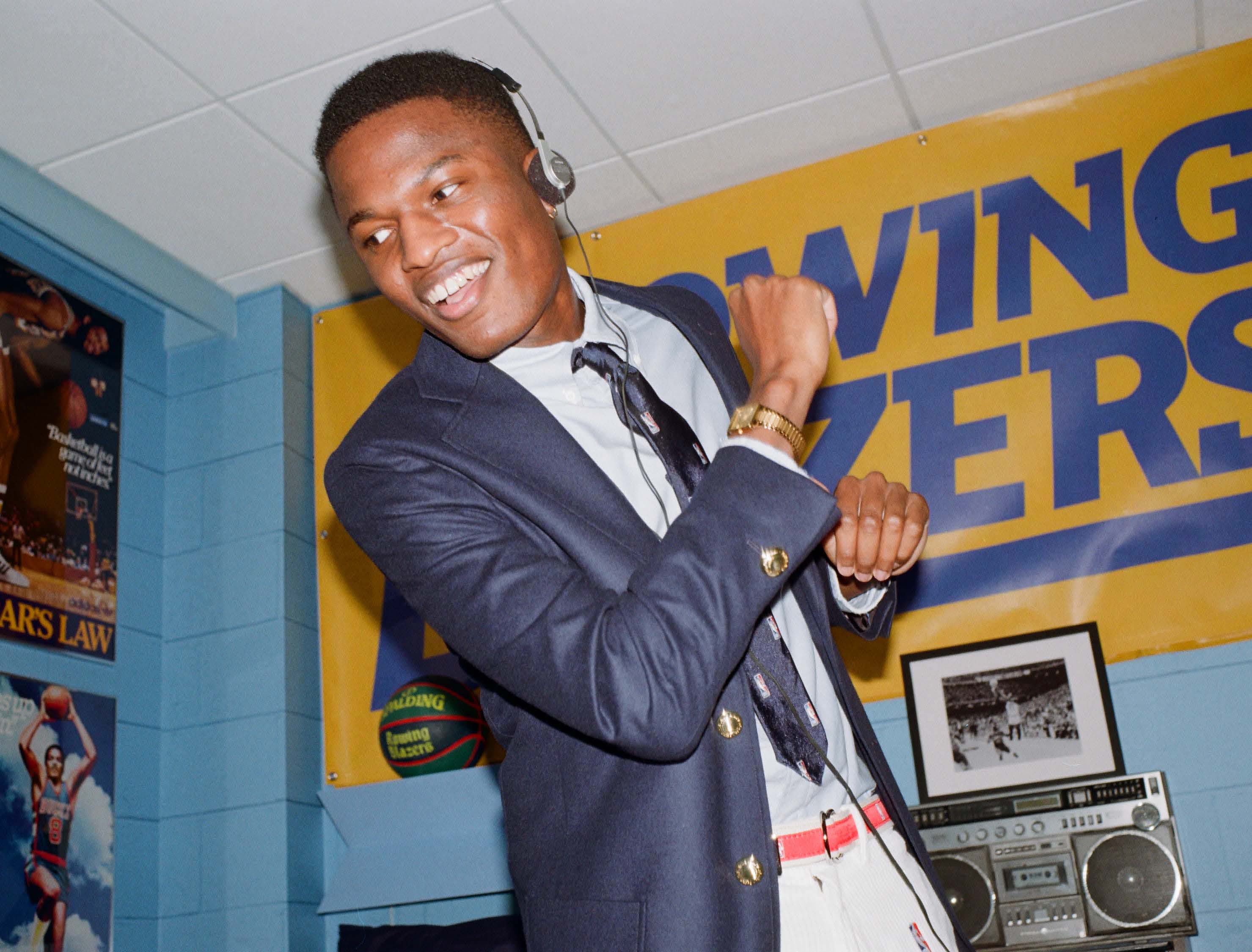 Model wearing the Chicago Bulls Rugby Shirt and White Corduroy NBA Logo Trousers in a recreation of one of Rowing Blazers' favorite player's freshman dorm room located at The Graduate Chapel Hill.