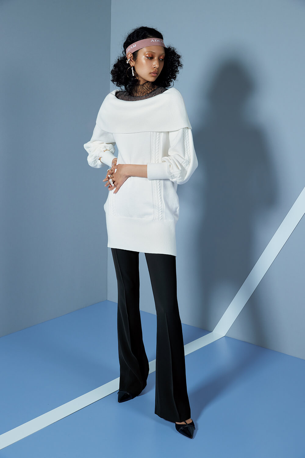 model in white knit top and black pants