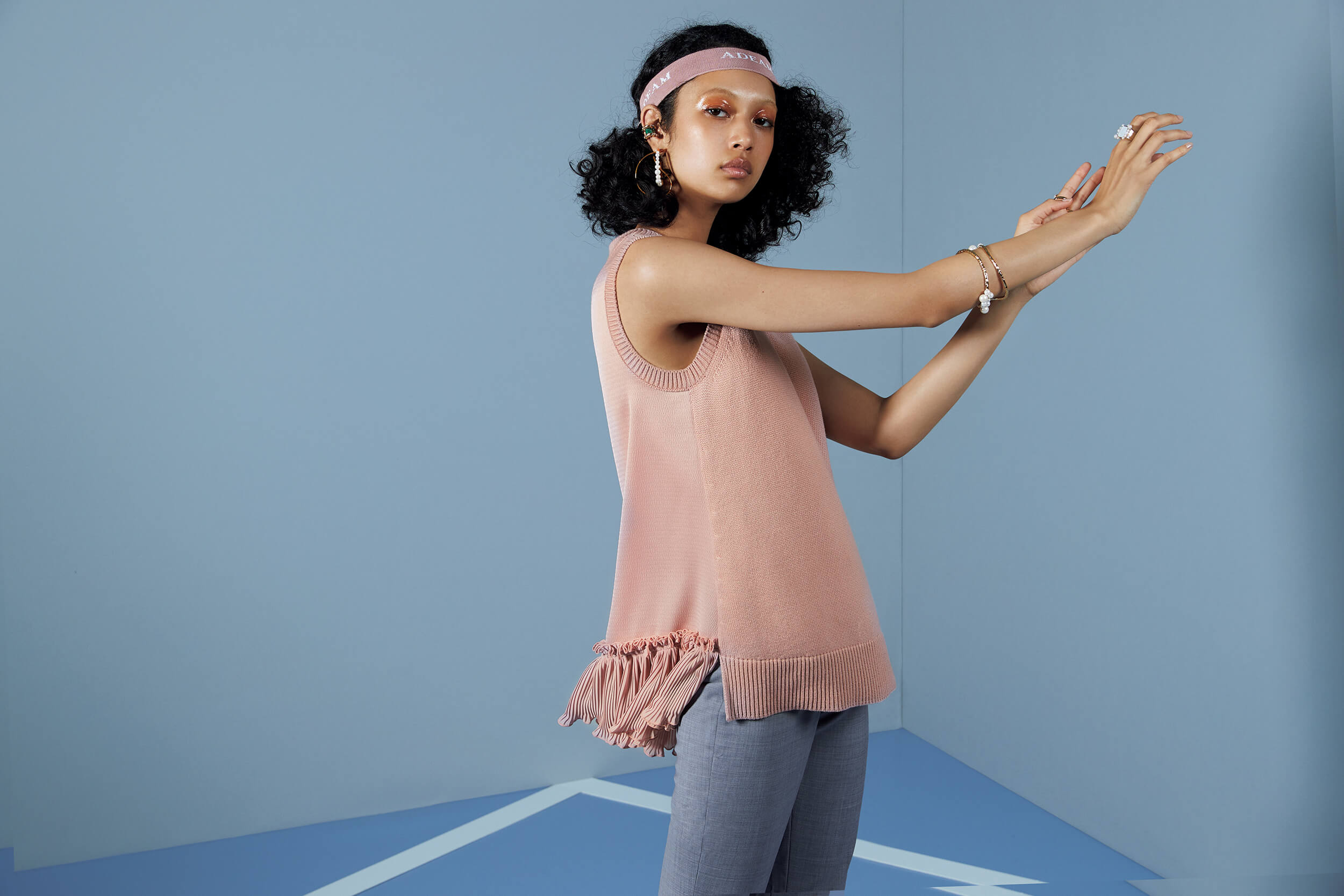 model in peach top and gray pants