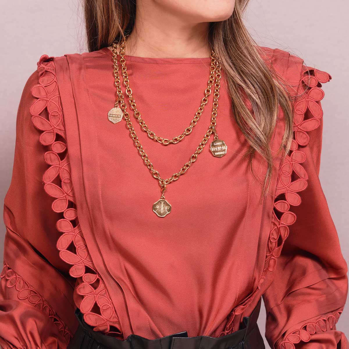 Three Octopi Pendants attached to Gold Chain Necklace on neck of woman with fair skin and salmon blouse