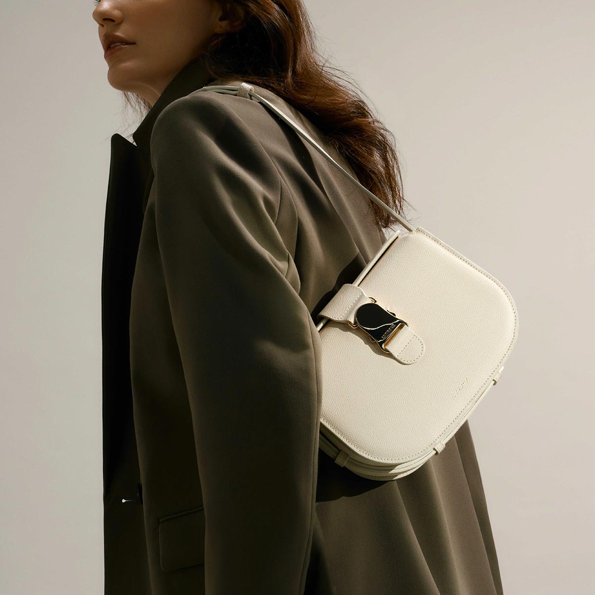 brunette woman wearing a trench coat and white crossbody in cream over the shoulder