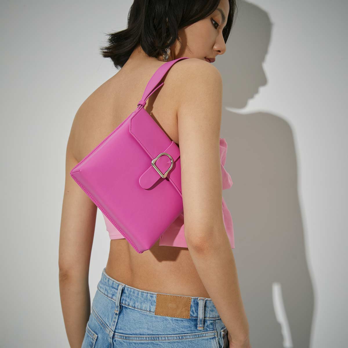 woman in a barbiecore pink look with pink leather handbag on her shoulder
