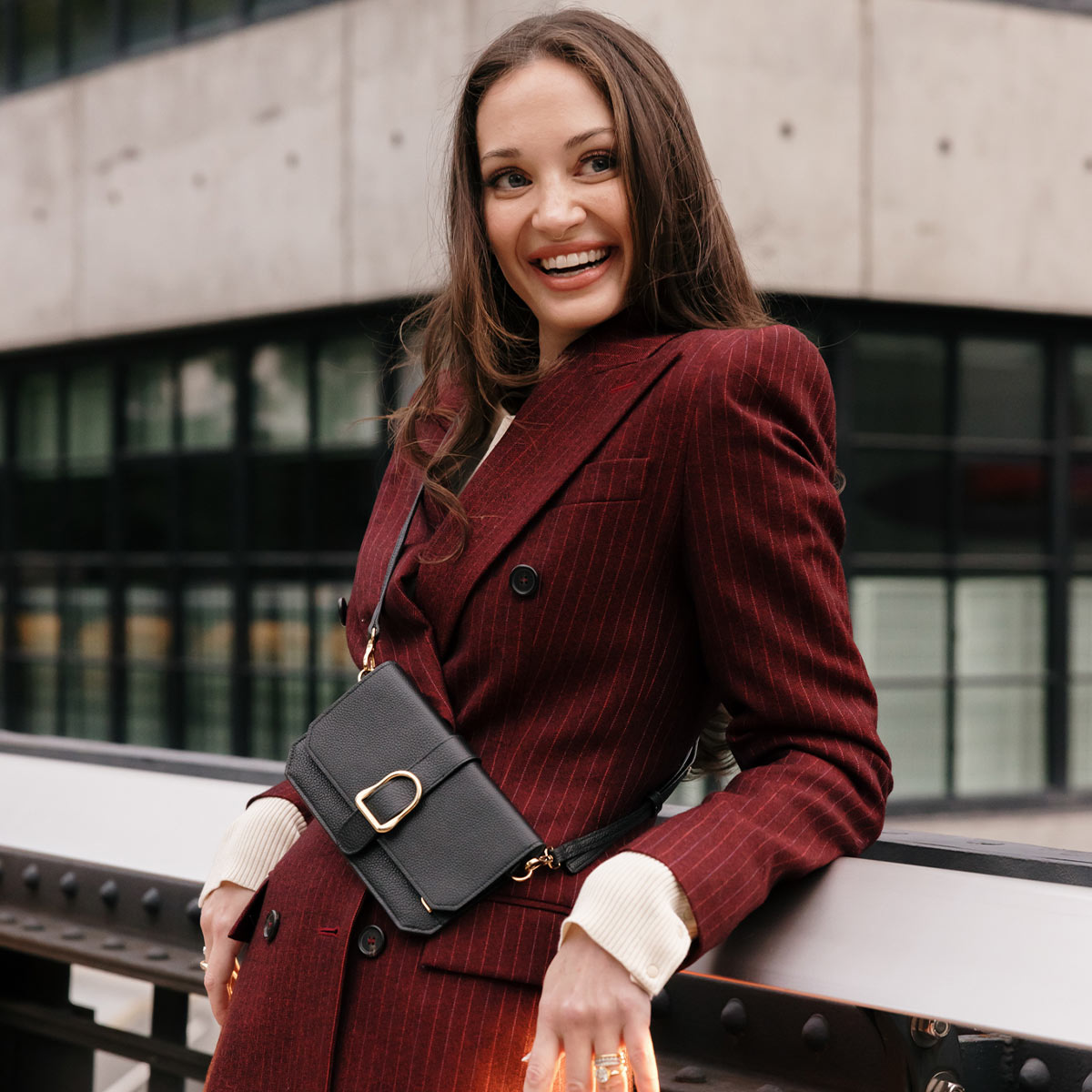brunette woman wearing red blazer and black leather phone crossbody