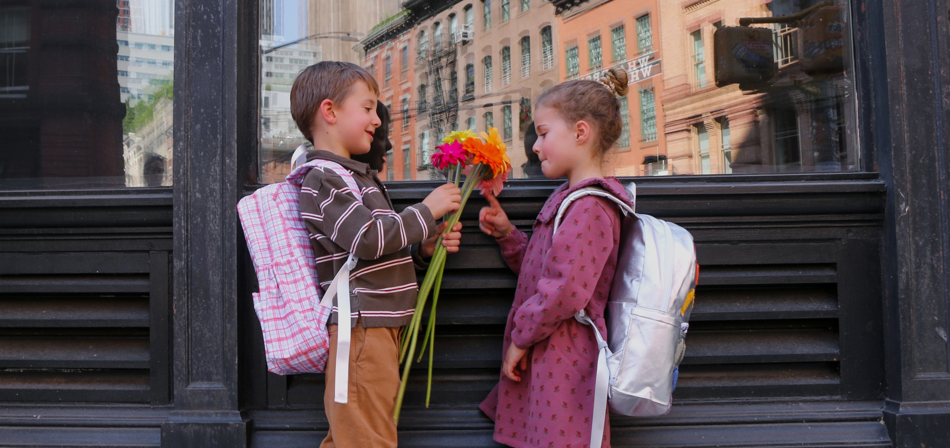 young girl and boy wearing danrie clothes holding flowers and wearing backpacks
