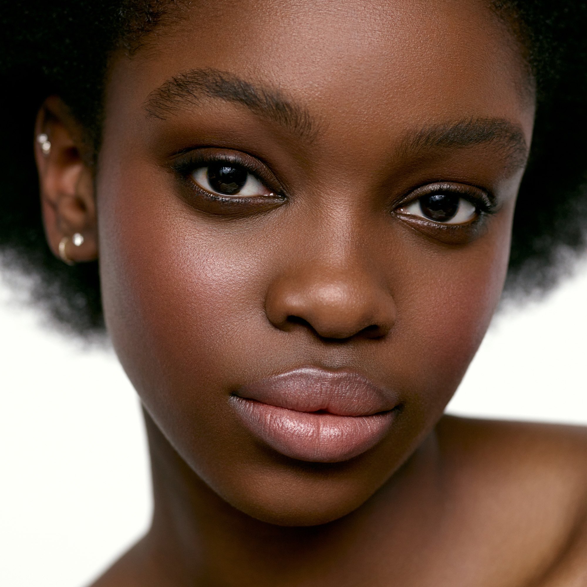 Image of a deep skin tone model wearing the Cream Blush Refillable Cheek & Lip Color in Foxglove 1