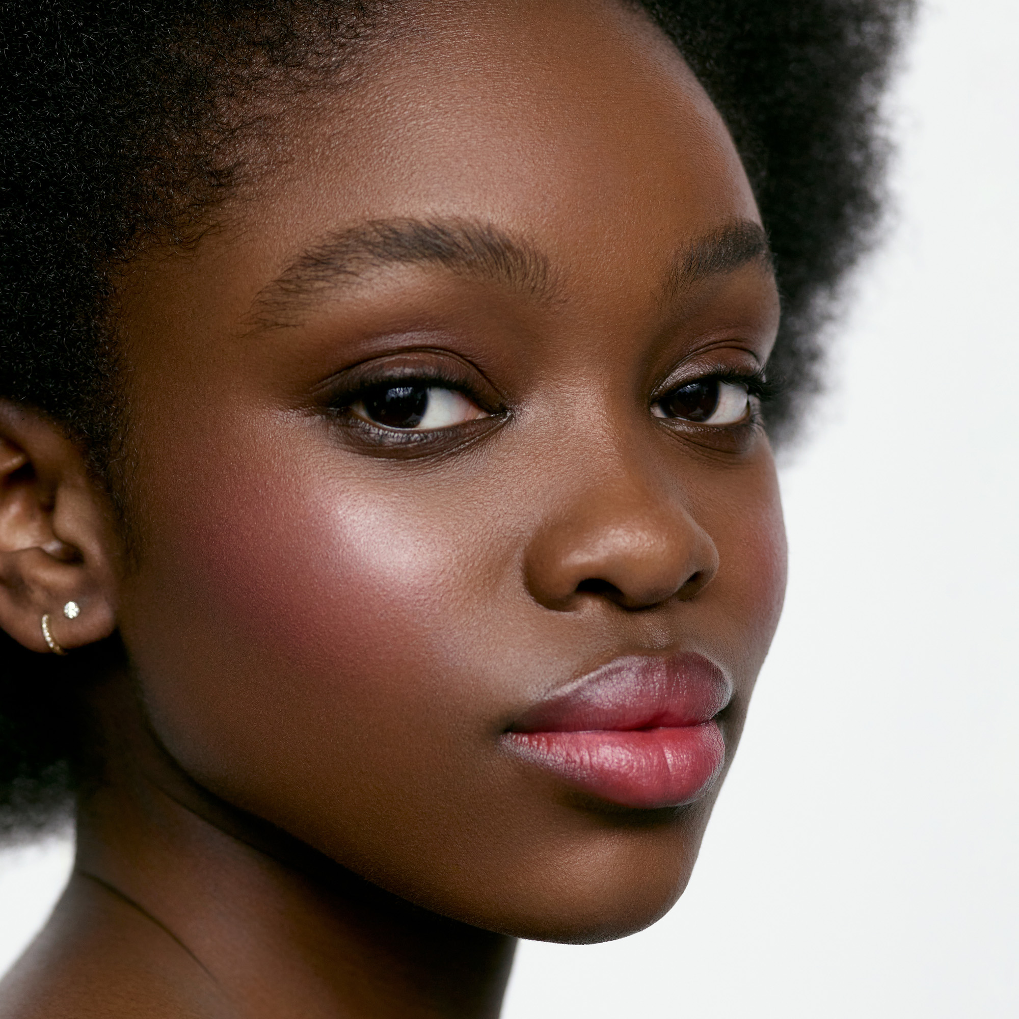 Image of a deep skin tone model wearing the Cream Blush Refillable Cheek & Lip Color in Azalea 1