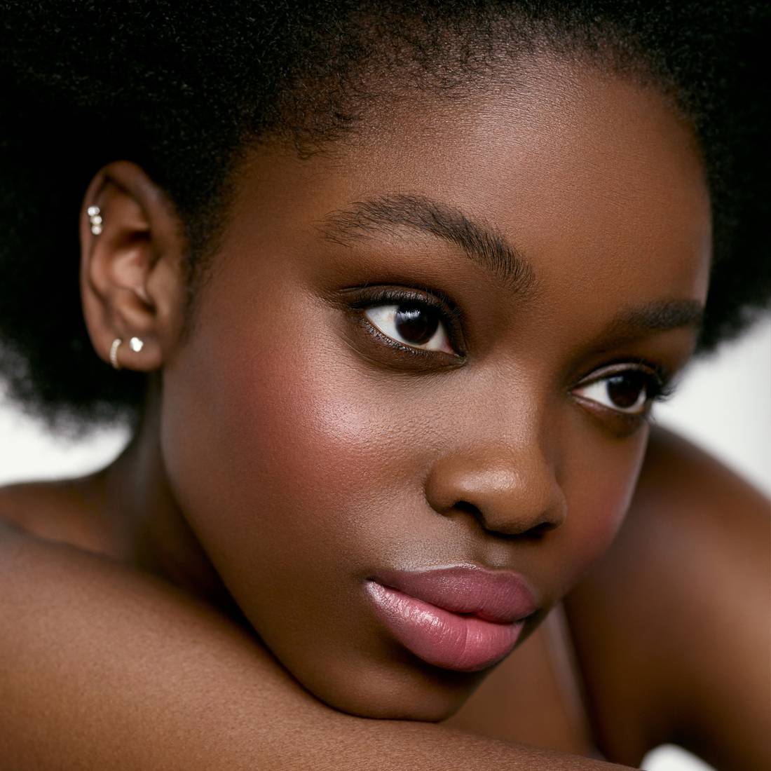 Image of a deep skin tone model wearing the Cream Blush Refillable Cheek & Lip Color in Ophelia 1
