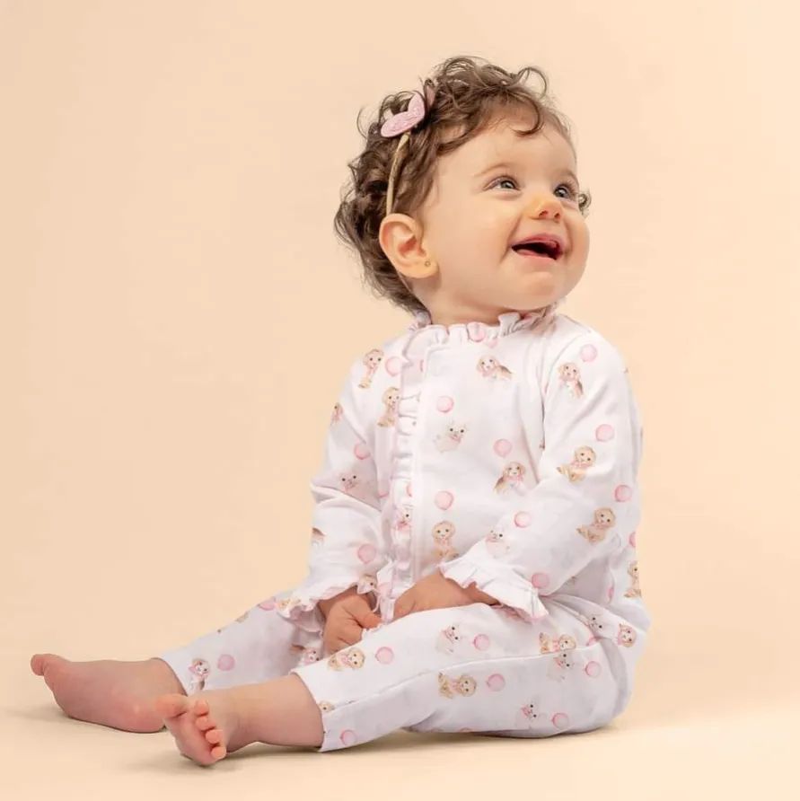 baby girl sitting and smiling wearing white ruffle onesie
