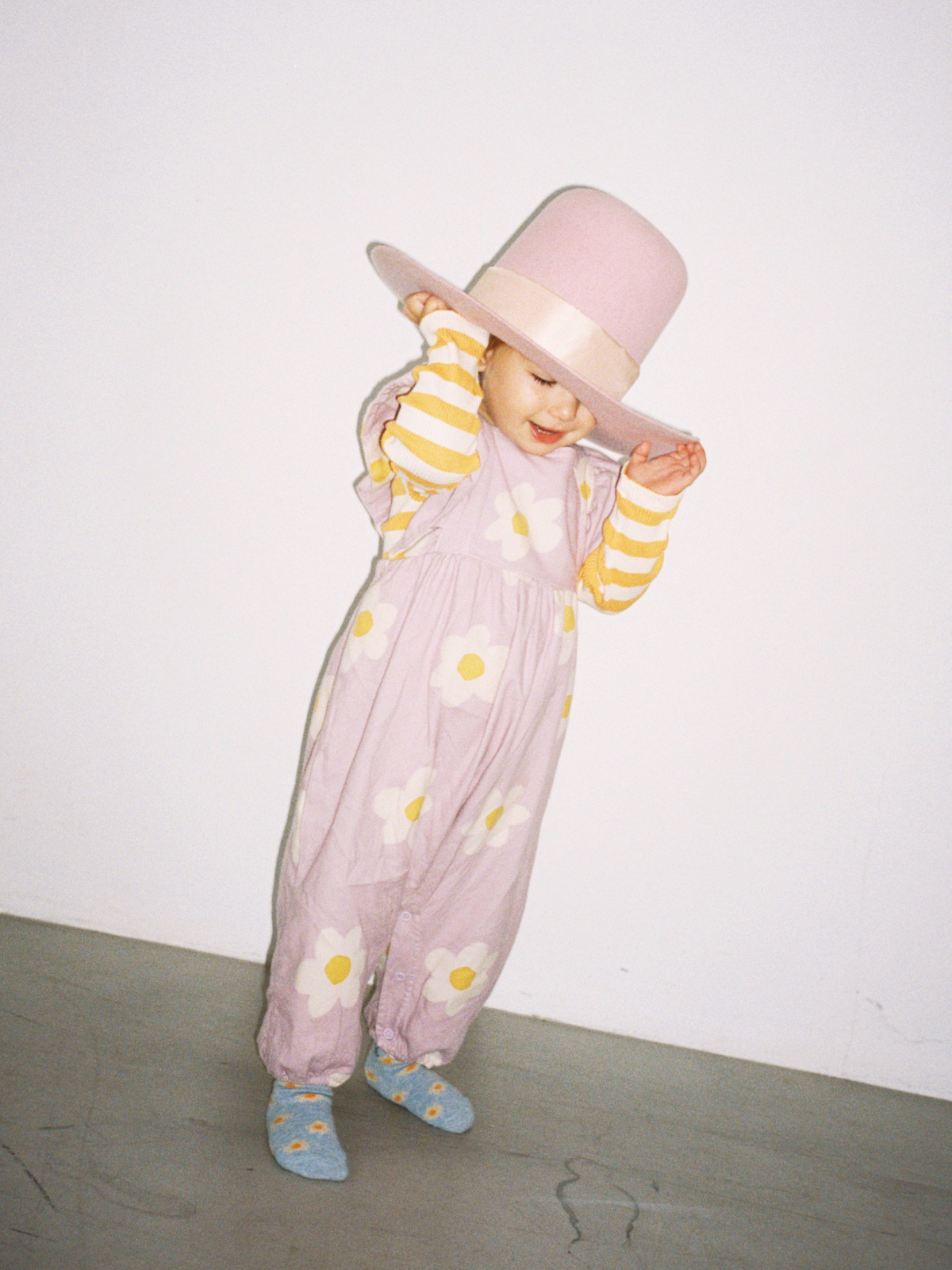baby girl wearing purple floral jumpsuit with a large purple hat on