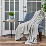 A Cosy House Collection Everyday Fleece Blanket is displayed on a chair.