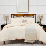 A neatly made bed covered with Cosy House Collection bedding.