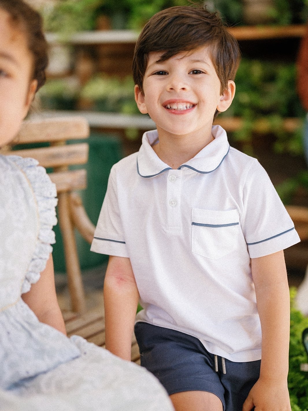 young boy wearing baybala polo. White polo with navy blue trim