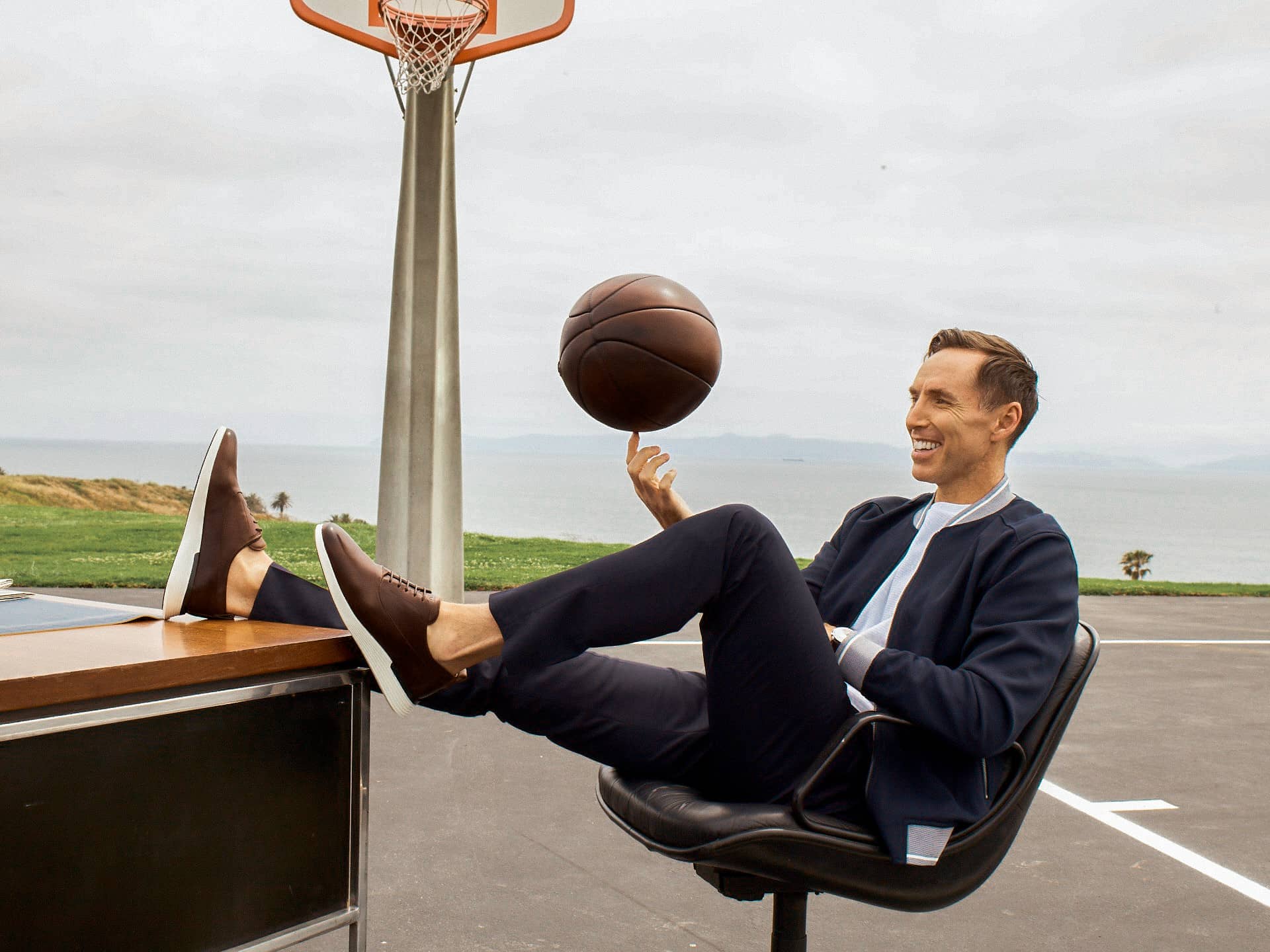 Steve Nash spinning a basketball wearing hybrid dress shoe Crossover™ Longwing in Maple