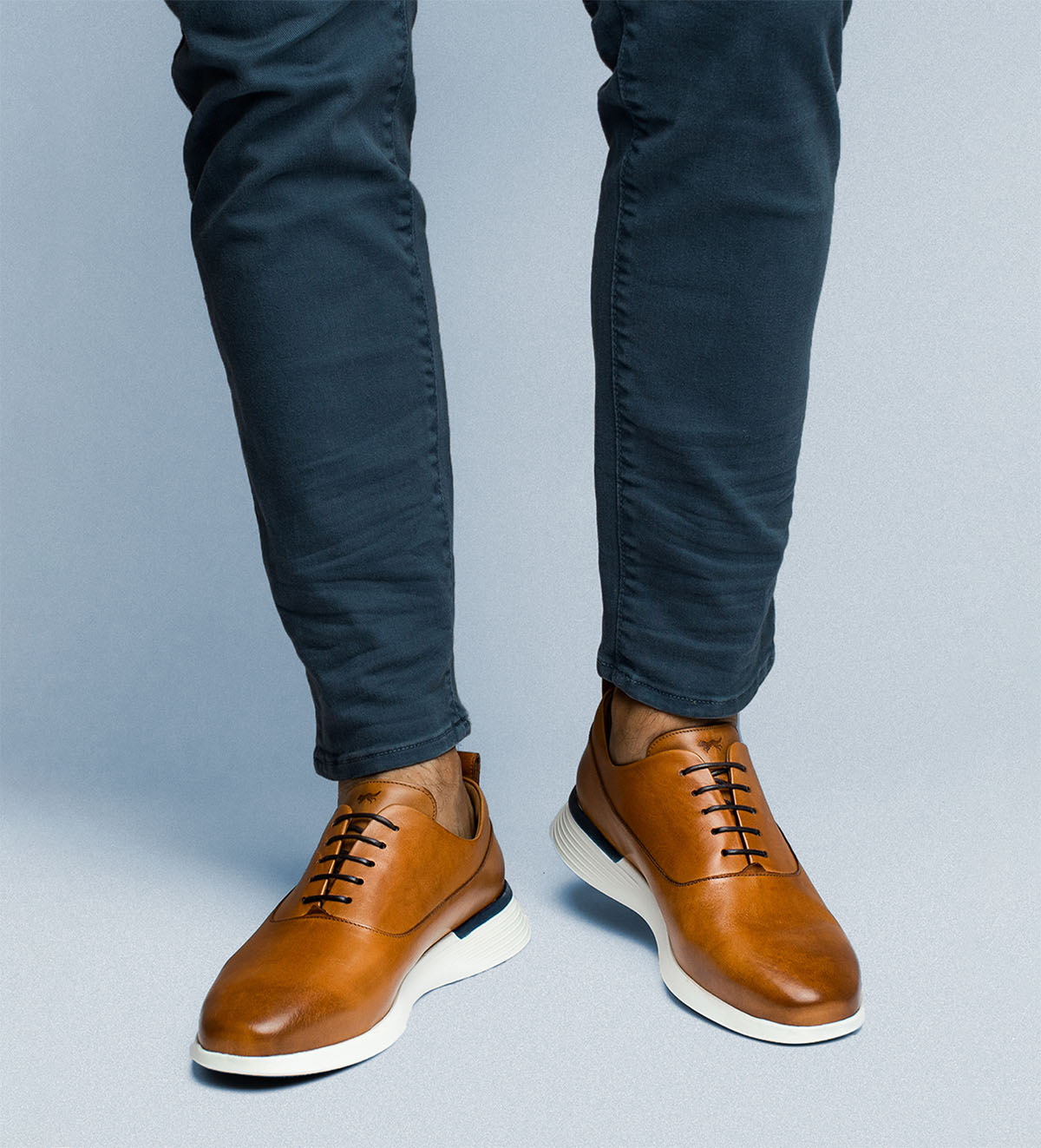 Knee down view of man standing wearing hybrid dress shoe Crossover™ Longwing in Honey