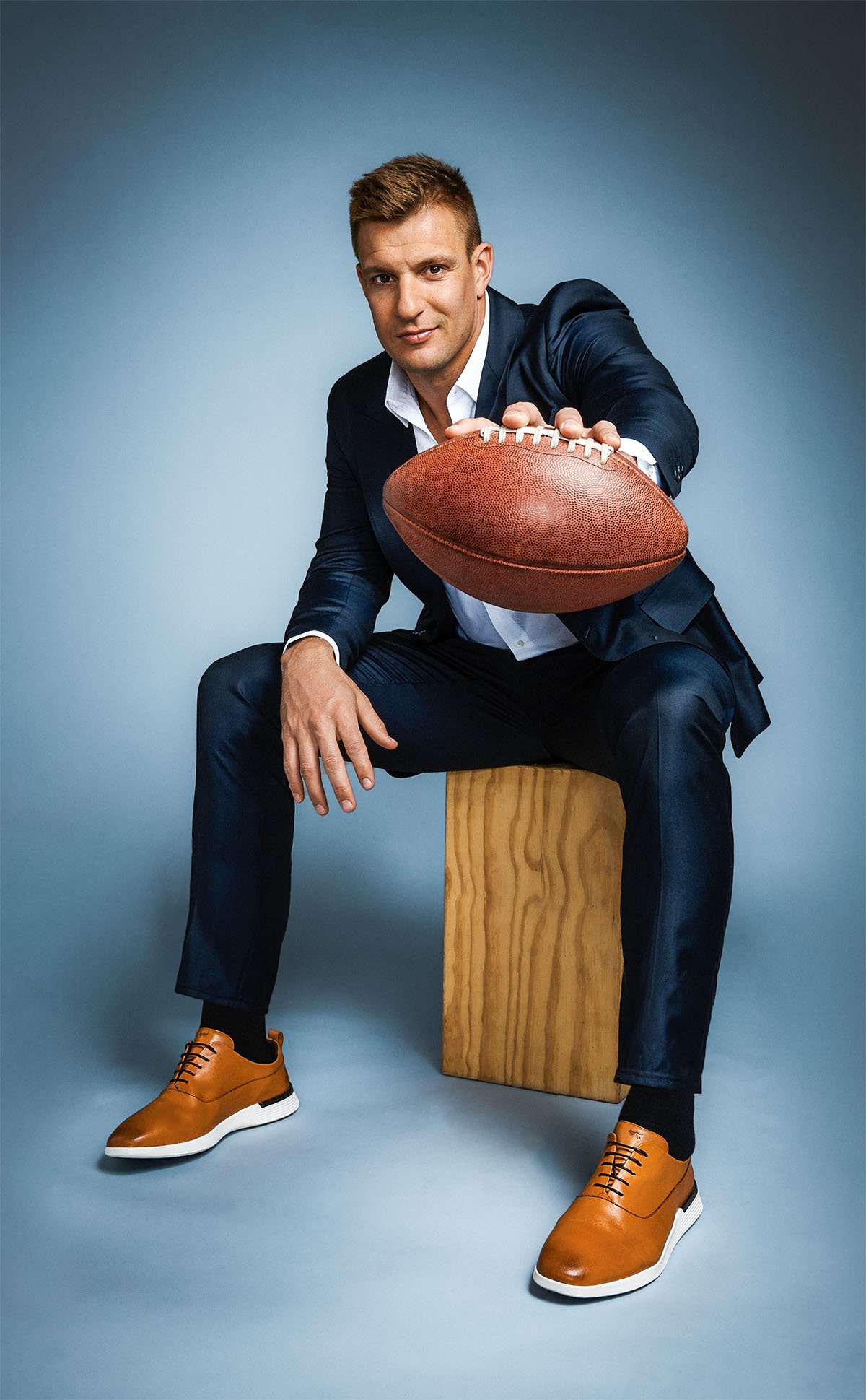 Rob Gronkowski sitting wearing hybrid dress shoe Crossover™ Longwing in Honey