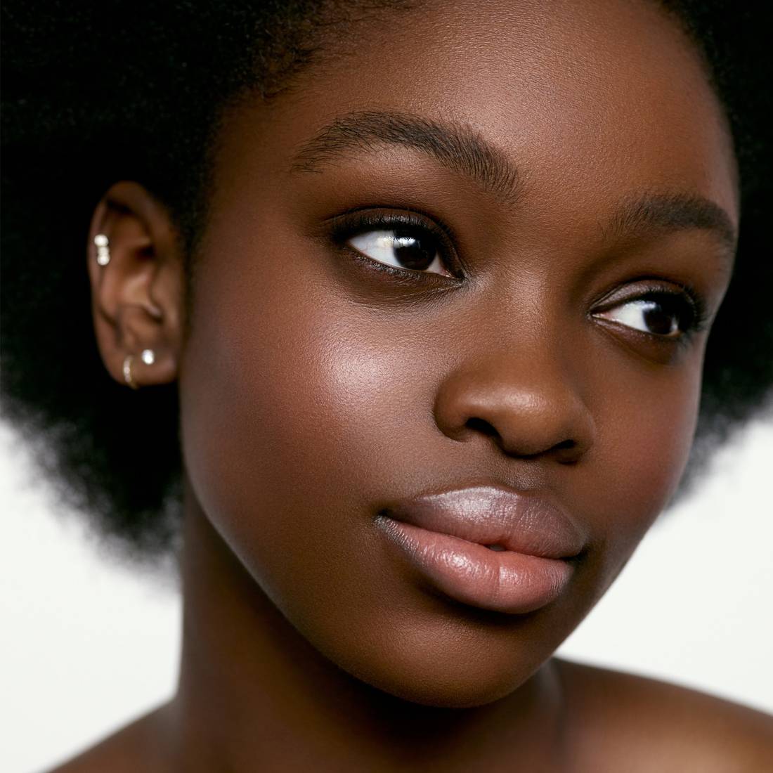 Image of a deep skin tone model wearing the Cream Blush Refillable Cheek & Lip Color in Wisteria 1