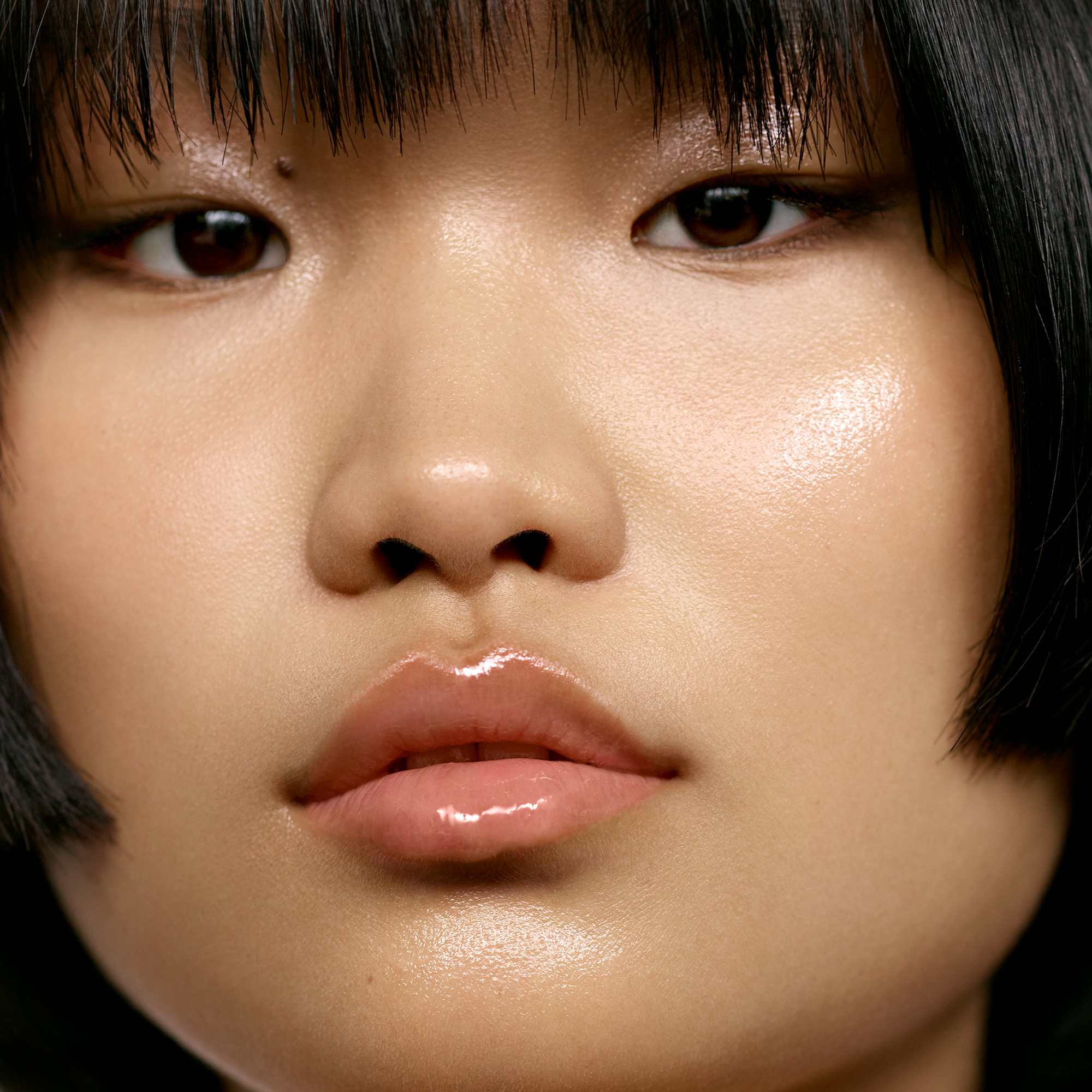 Medium skin tone model wearing lip treatment balm.