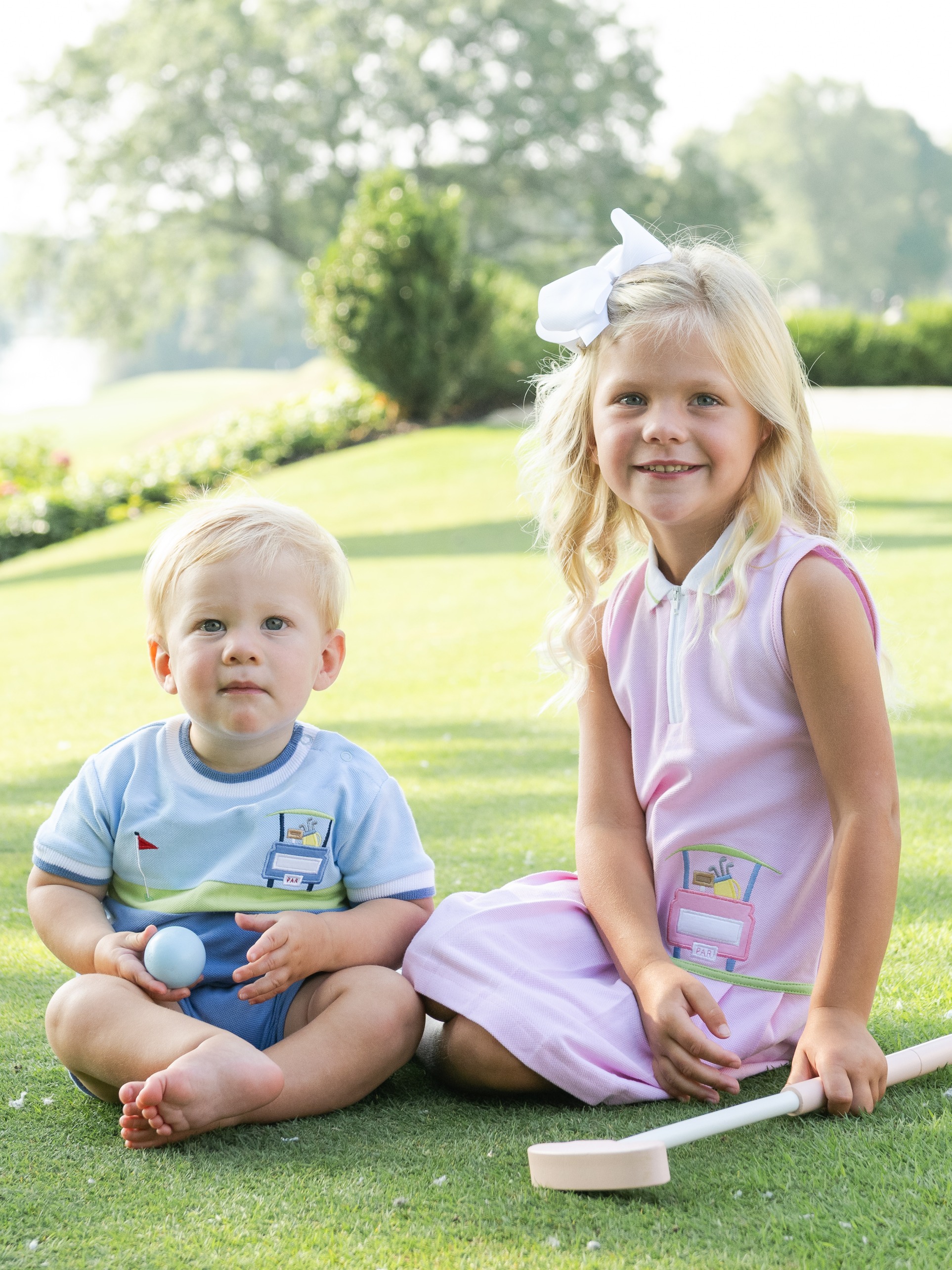 girl and boy wearing golf outfits on golf course