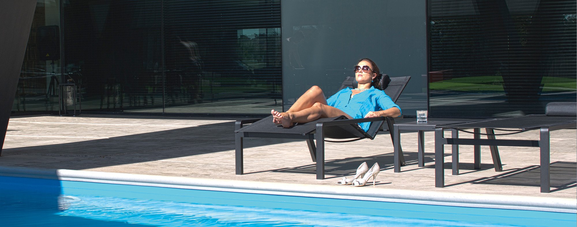 Woman resting on Alura 195 adjustable sun lounger by the pool