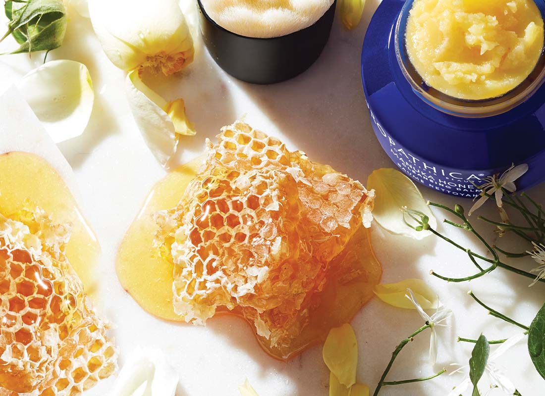 Manuka Honey Cleansing Balm and Brush on a table with honey
