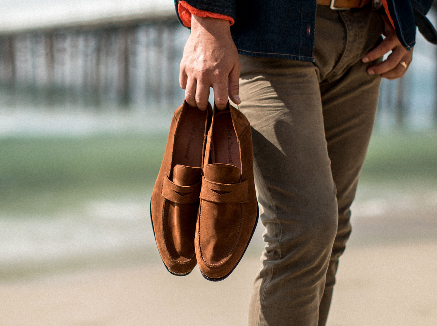 Waist down view of man holding dress shoe Monaco Loafer in Cognac brown 