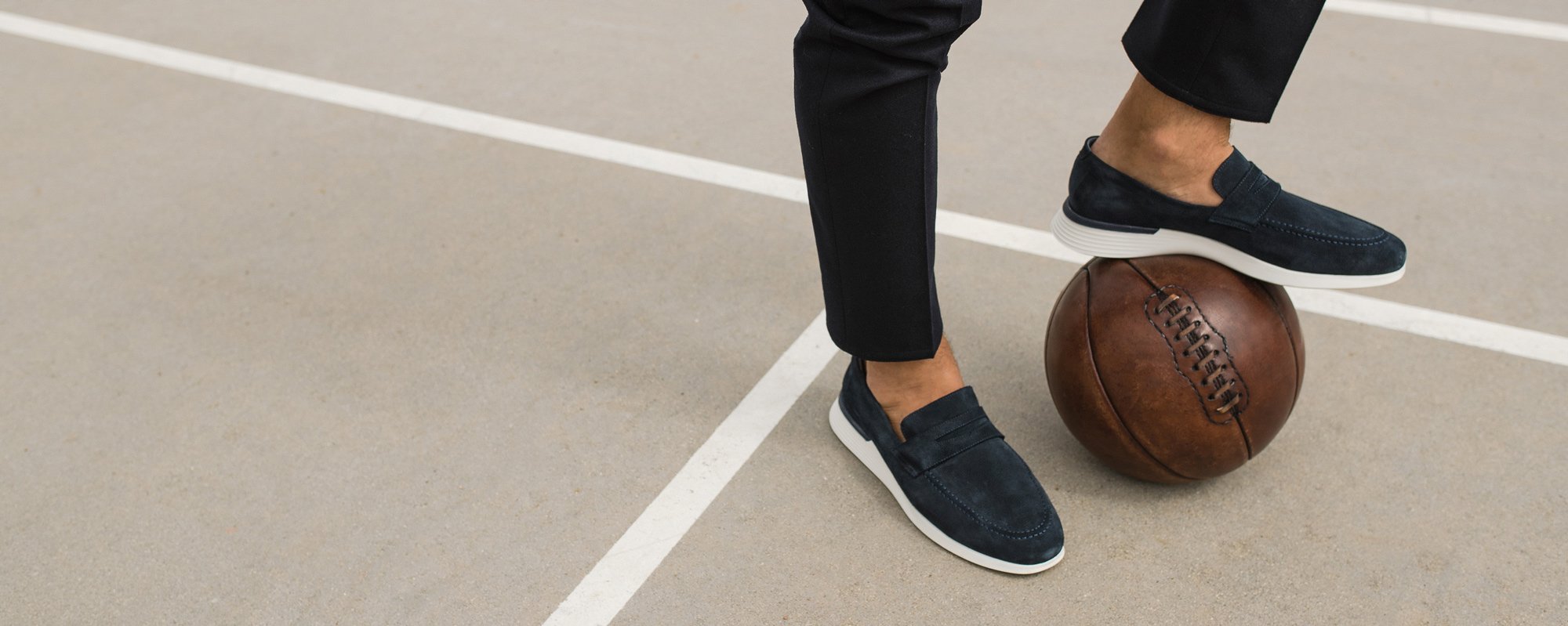Knee down view of man kicking a basketball wearing Hybrid Dress shoe Crossover Loafer in Navy