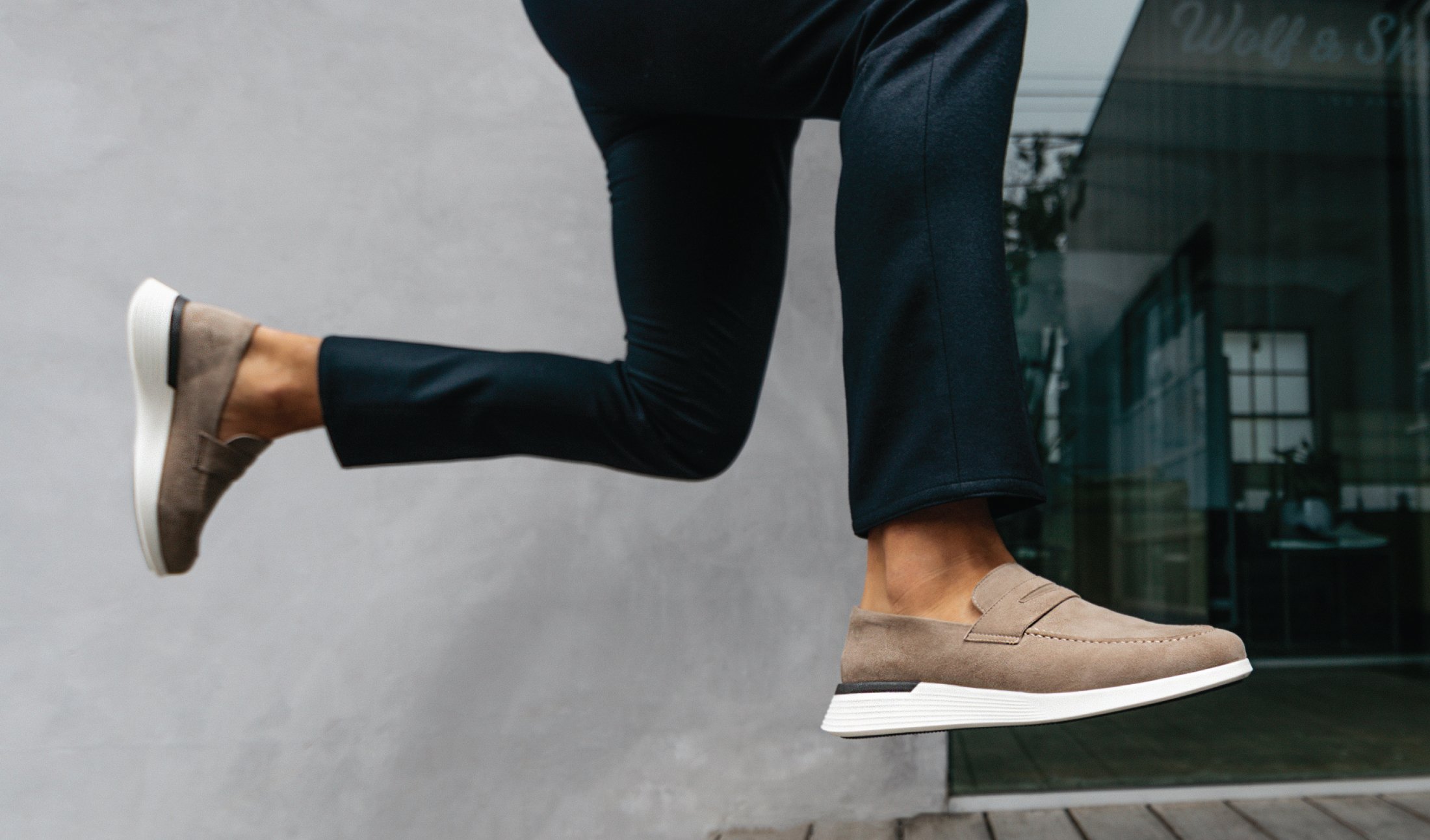 Knee down view of man jumping wearing Hybrid Dress shoe Crossover Loafer in Stone
