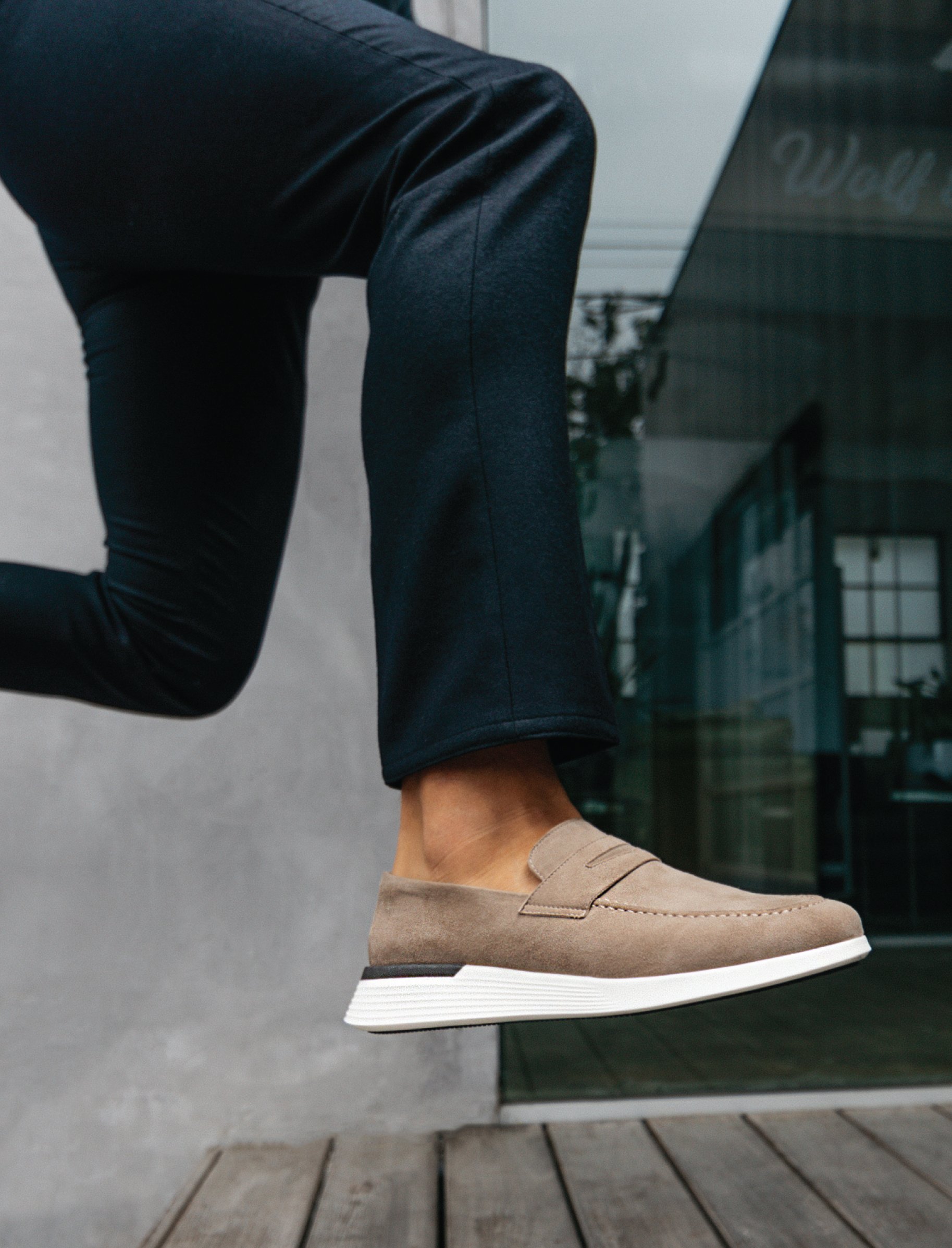 Knee down view of man jumping wearing Hybrid Dress shoe Crossover Loafer in Stone