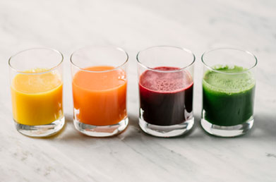 Small glasses of colorful wellness shots made with Navitas Superfood+ Greens Blend