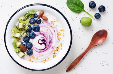 Bowl of yogurt made with Navitas Superfood+ Berry Blend and topped with fresh ingredients
