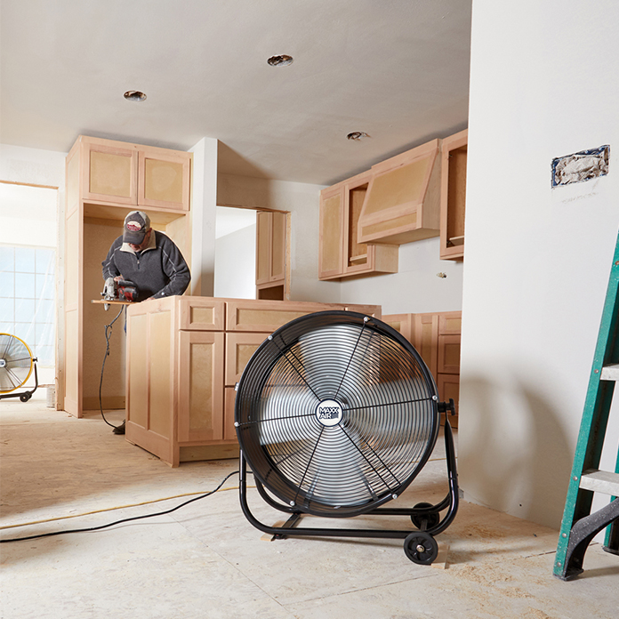 Two 24 in. tilt fans in the floor configuration line a kitchen walkway pulling fresh, cool air into the room while a carpenter works.