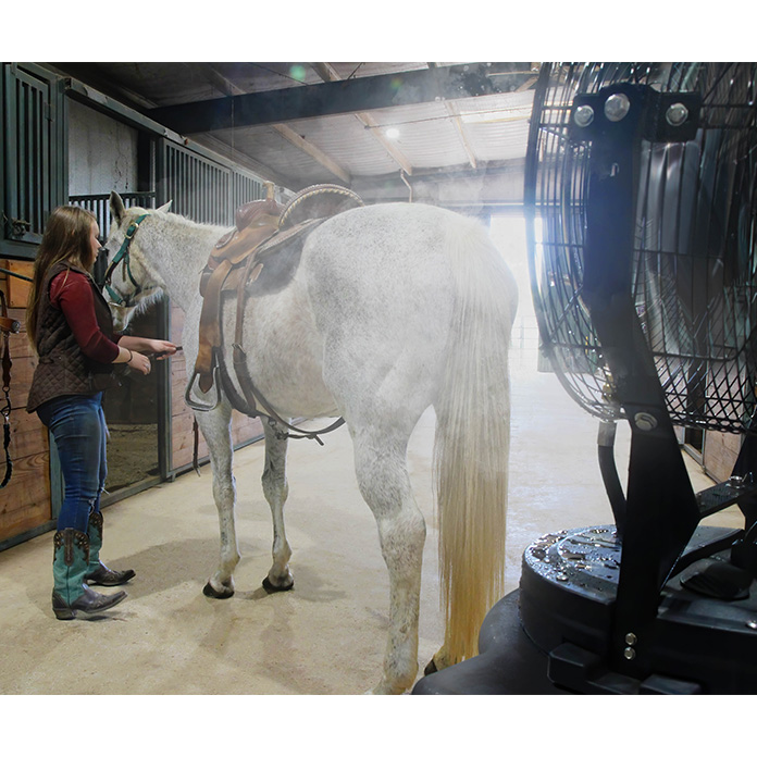 A Maxx Air misting fan cools a horse and rider while tacking up in the barn.