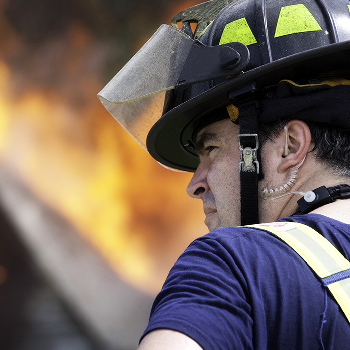 Firefighter cools down while the flames are being battled by others. Misting fans at fire rehab stations help ensure the physical well-being of firefighters as they work.