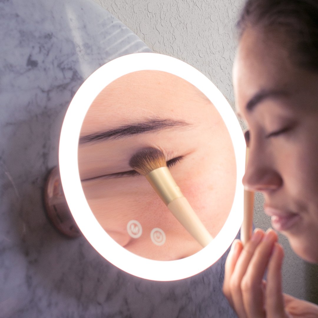 Woman using the lana 10x magnifying mirror to apply eyeshadow