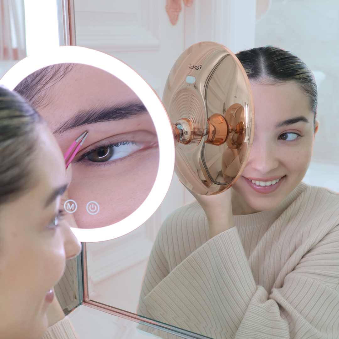 Woman using the lana 10x magnifying mirror to tweeze her eyebrows