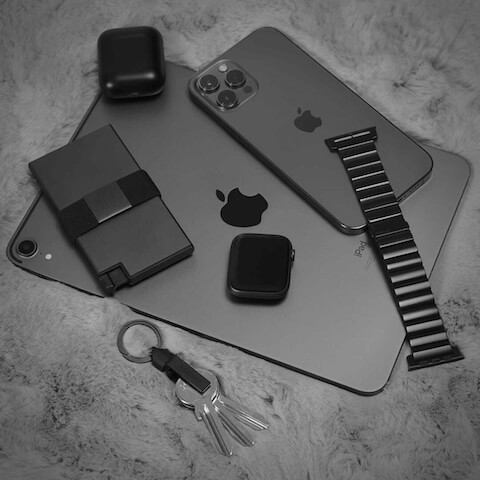 Aluminum wallet, Ekster key holder, smartwatch, iphone and iPad sitting on a marble table top
