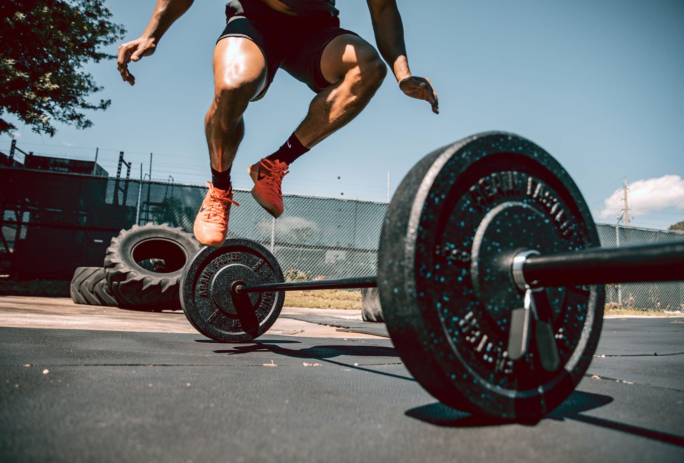 man performing burpee over barbell