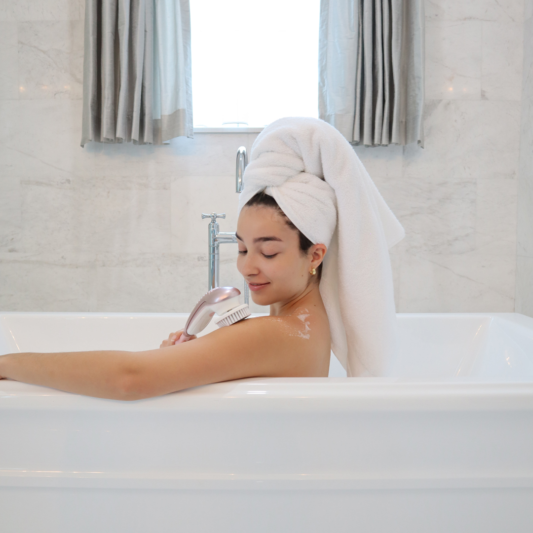 Woman using the cora 7 full body spin brush to wash her back 