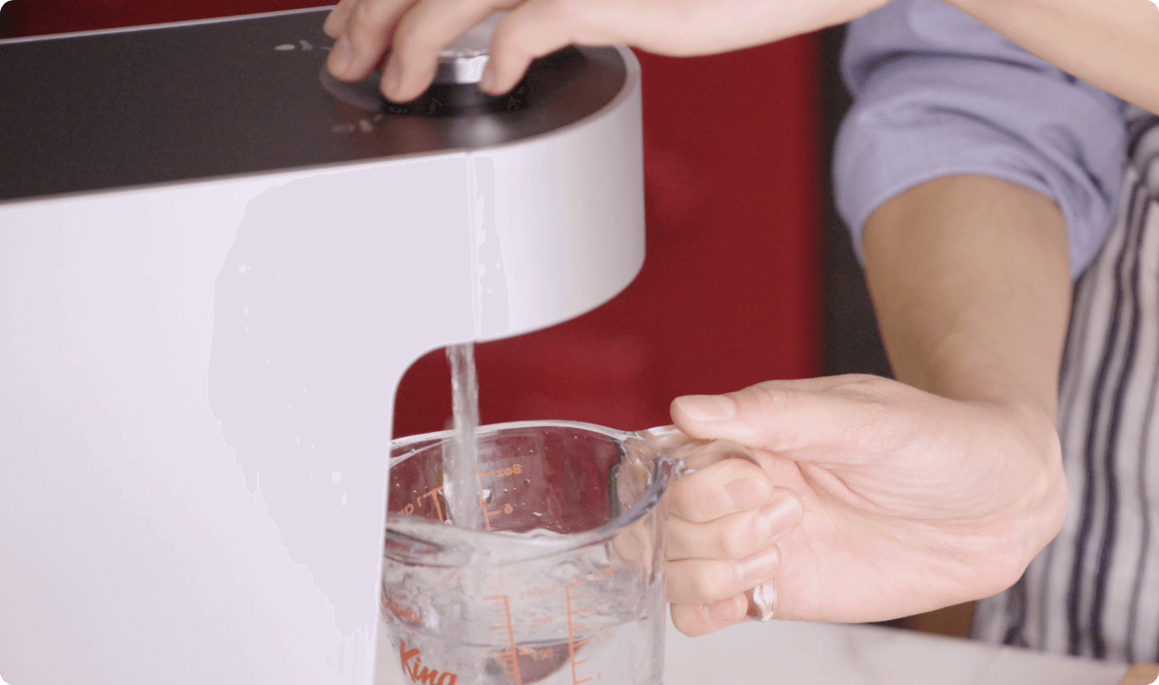 Person filling up cup with Coway Aquamega 100