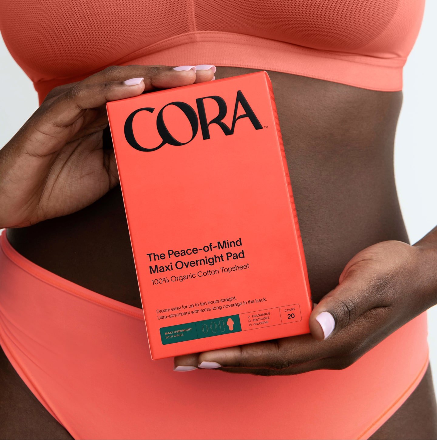A close up of a person holding a box of maxi pads in front of their stomach
