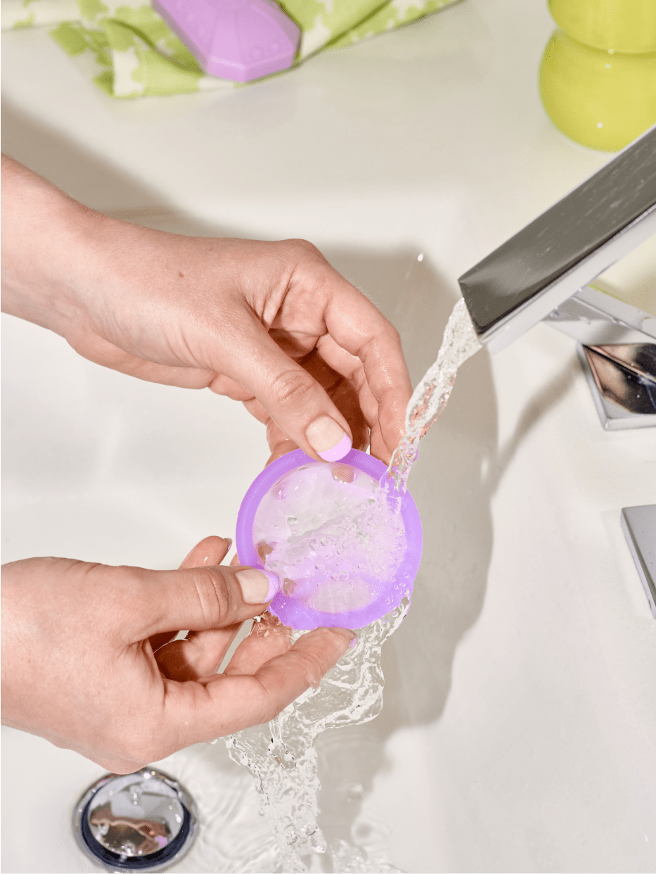 A close up of a disc being washed under a faucet