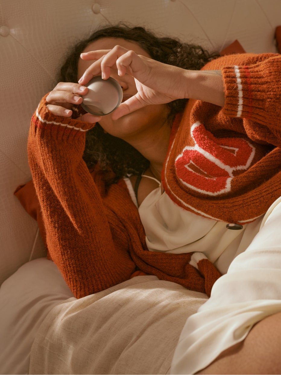 A person laying on a bed holding a period disc