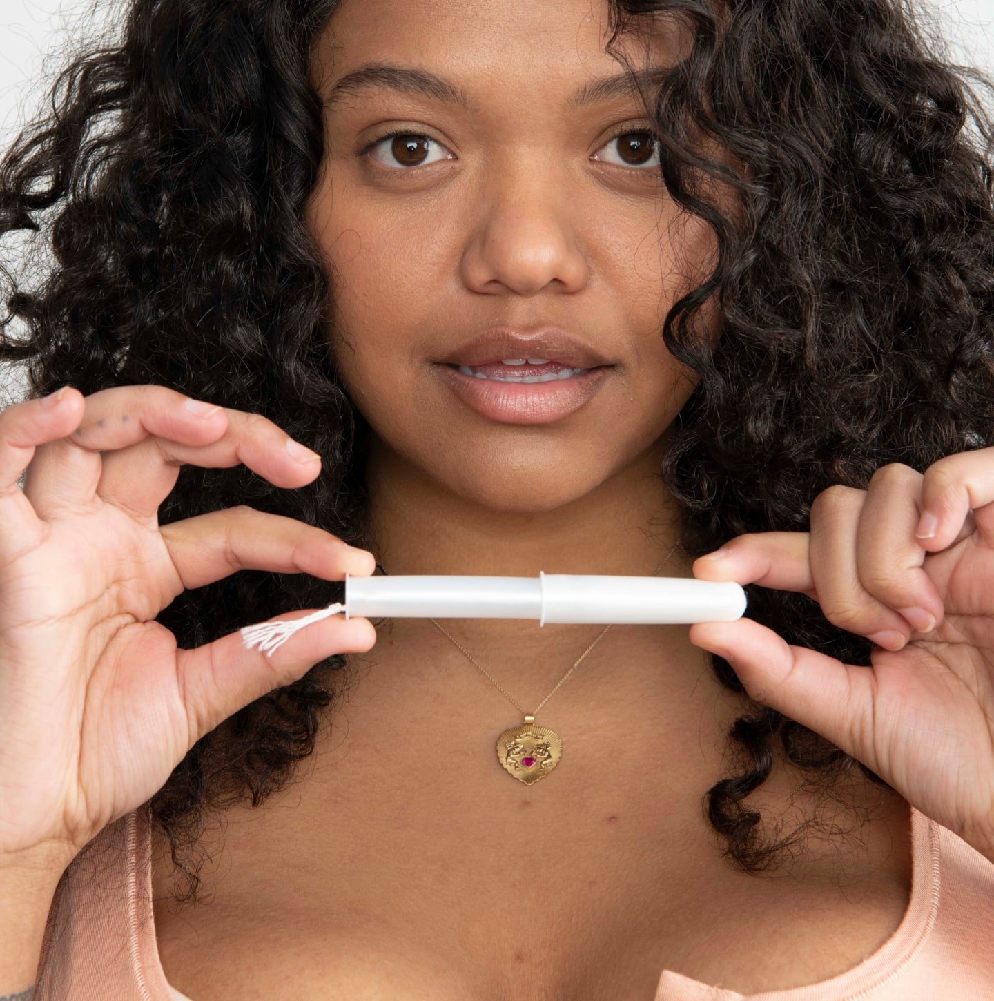 A close up of a person holding a tampon applicator