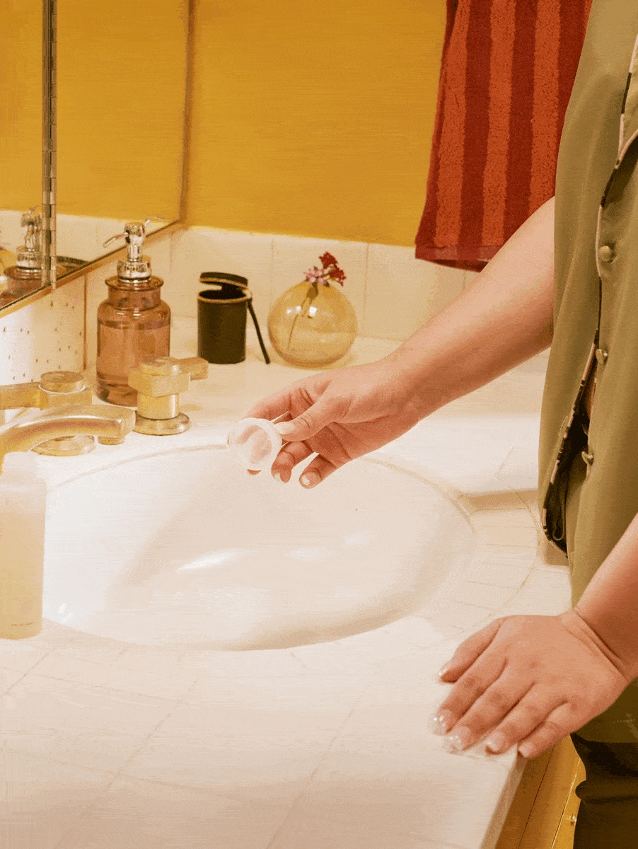 A GIF of a woman squeezing the Easy-Does-It Cup over the sink